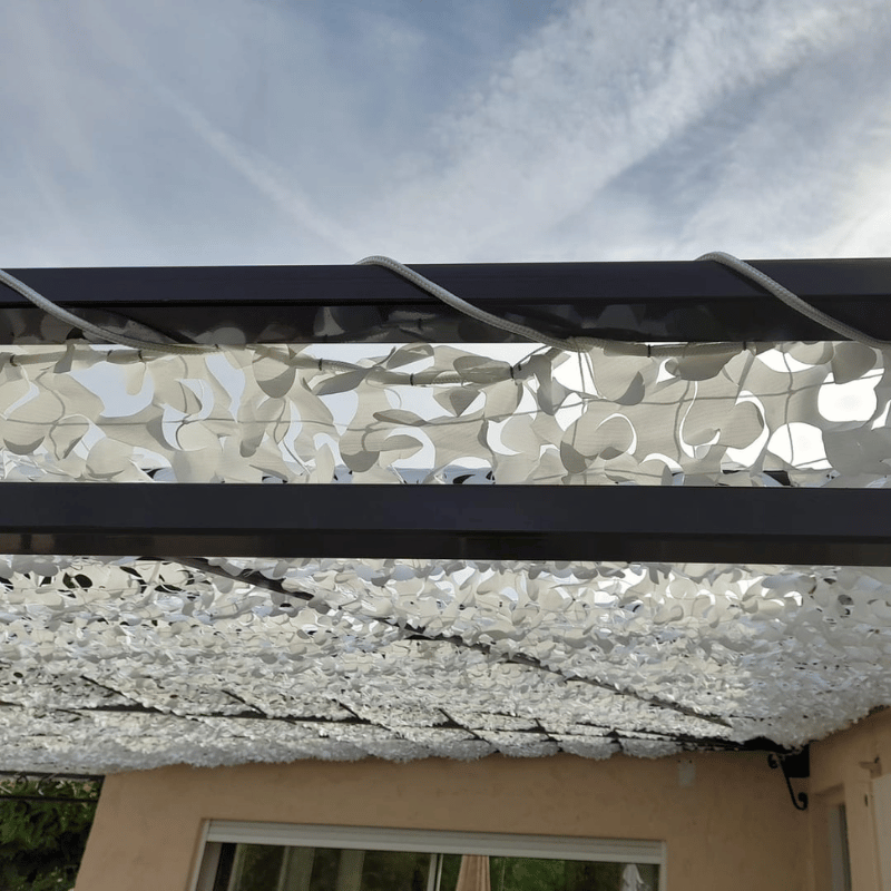 Cuerda de poliéster trenzado fijando una red de camuflaje blanca sobre una pérgola