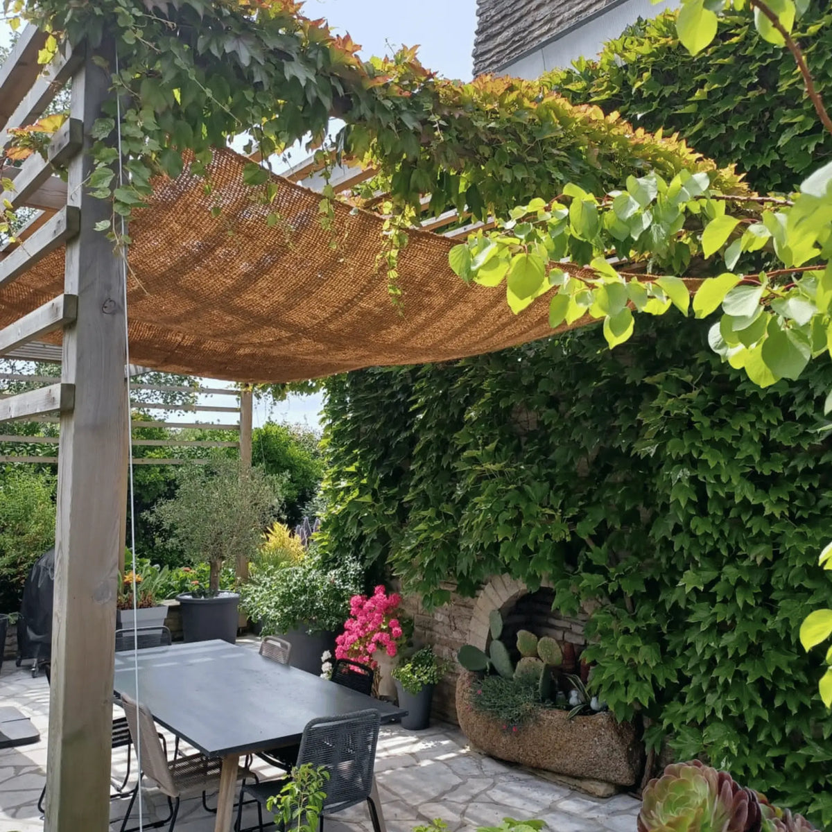 Toldo de fibra de coco sobre una mesa de jardín con enredadera