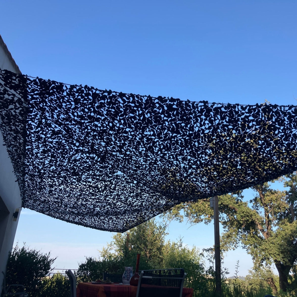 Red de camuflaje triangular negra tensada contra un cielo azul