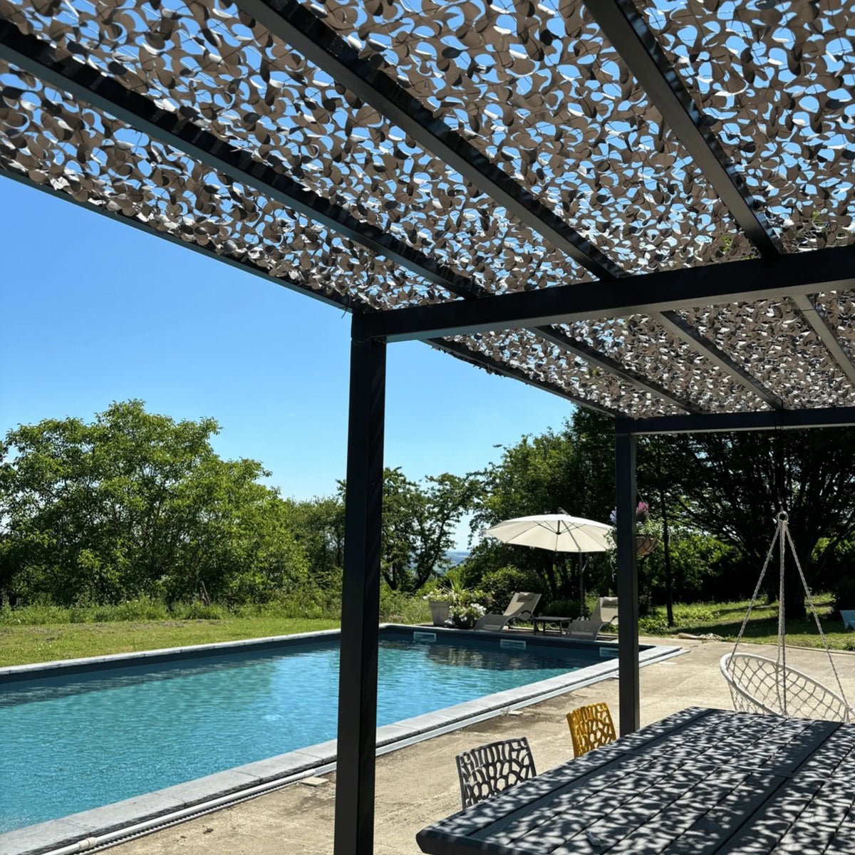 Red de camuflaje reforzada gris sobre una pérgola junto a la piscina