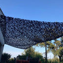 Red de camuflaje triangular negra tensada contra un cielo azul